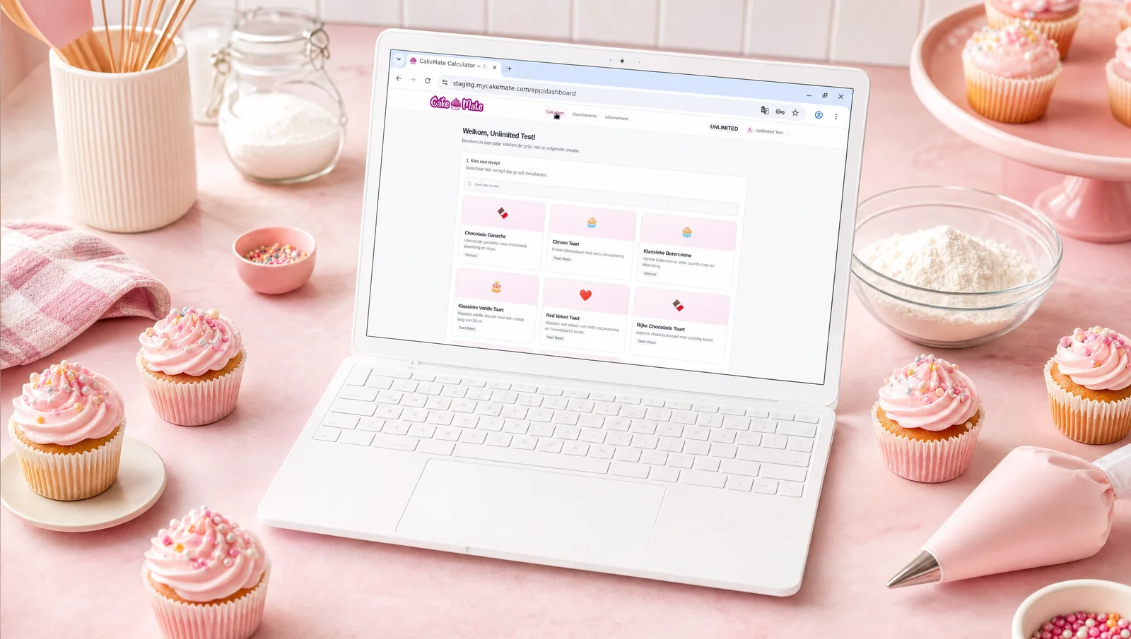 CakeMate dashboard op laptop omringd door roze cupcakes, spuitbag en bakkerij ingrediënten — eenvoudige receptberekening voor bakkers